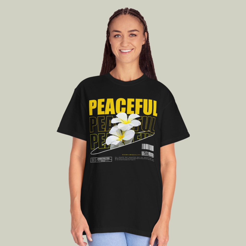 Black and yellow A woman wearing a black “Peaceful” t-shirt on a light olive green background.