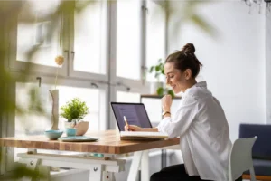 A smiling woman working from an office and searching for business ideas for women.