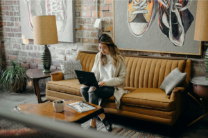 A woman sitting with a laptop on her lap, learning do you need a business license to sell on Etsy.