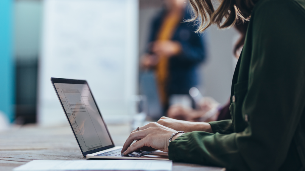 Etsy or Shopify Ease of store setup A woman sitting at a desk and using a laptop to read a comparison: Shopify vs Etsy.