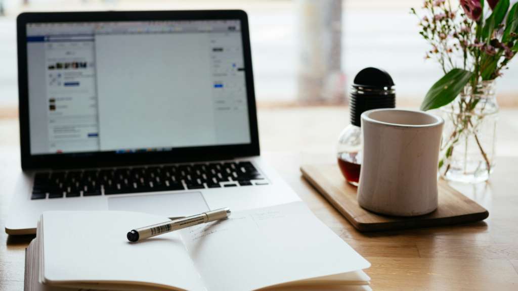 Freelance writing Side hustles for introverts A laptop and a notebook of a freelance copywriter on a desk in a cozy environment.