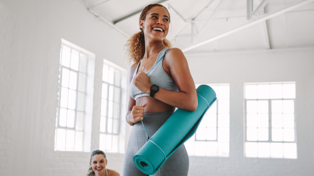 Health and fitness items Dropshipping business ideas A woman smiles while holding a yoga mat.