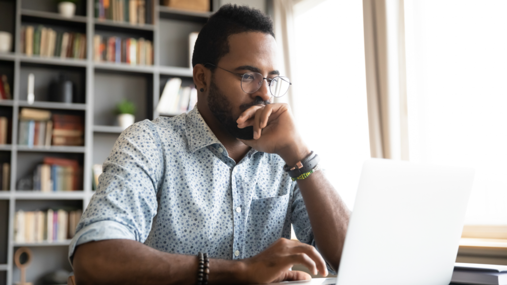 How to find dropshipping business ideas A man with glasses sits at a desk, focused on his laptop.