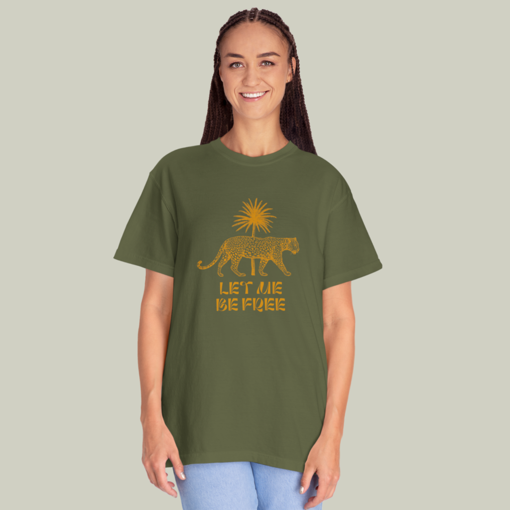 Olive and gold A woman wearing an olive and gold “Let me free” t-shirt on a light olive green background.