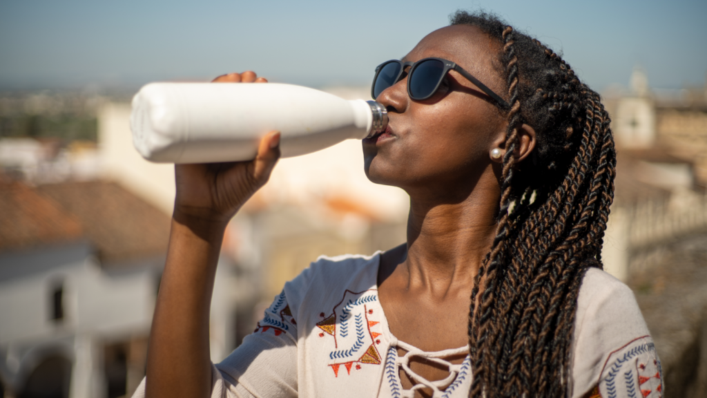 Reusable water bottles Conference swag A woman takes a drink from a bottle, appearing relaxed and content.