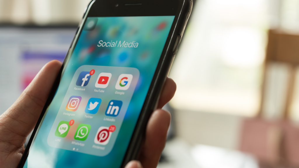 Run social media accounts Side hustles for introverts A person holding a phone with social media applications on it.