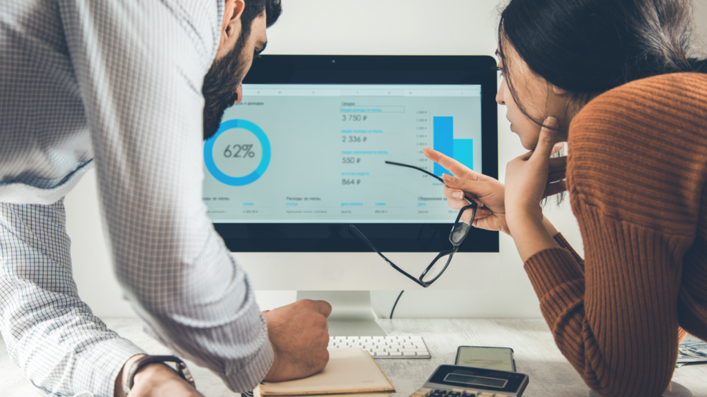 Shopify vs Etsy Analytics A man and a woman standing in front of a monitor and reviewing data.