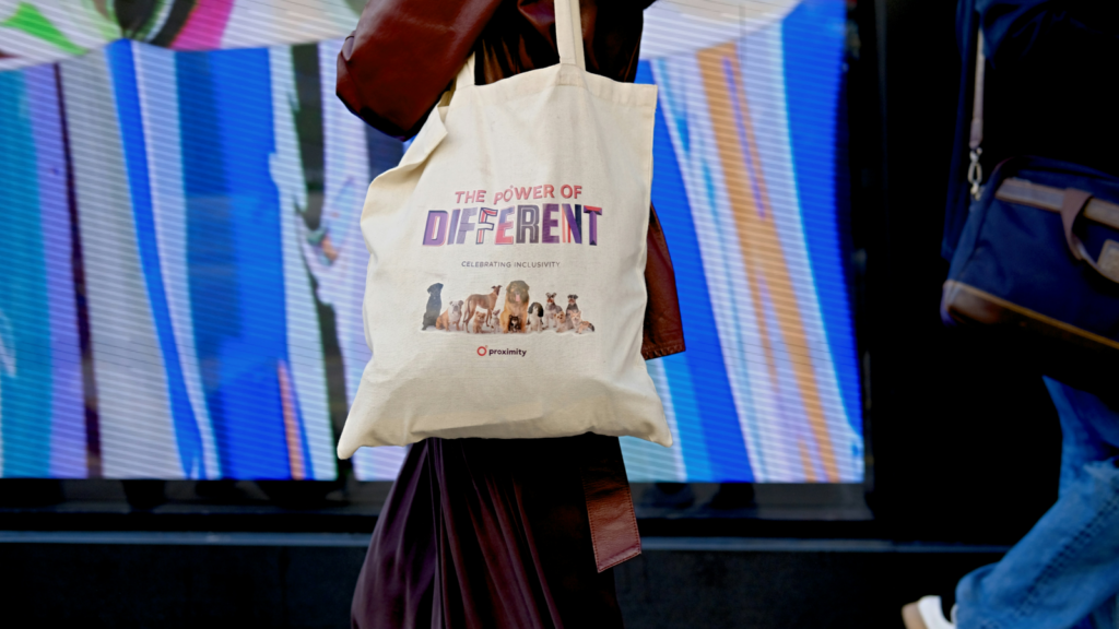 Tote bags Conference swag A woman strolls along the street, carrying a tote bag, surrounded by urban scenery.