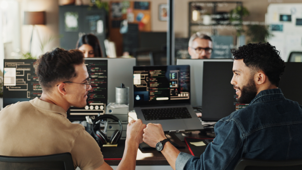 App or software development Side hustles that pay well Two men seated at a desk, each working on their own computer, focused on their tasks.