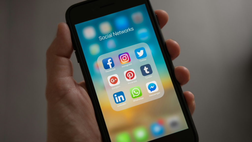 Best social media platforms for affiliate marketing A person holding a mobile phone in one hand with multiple social media app icons on the screen.