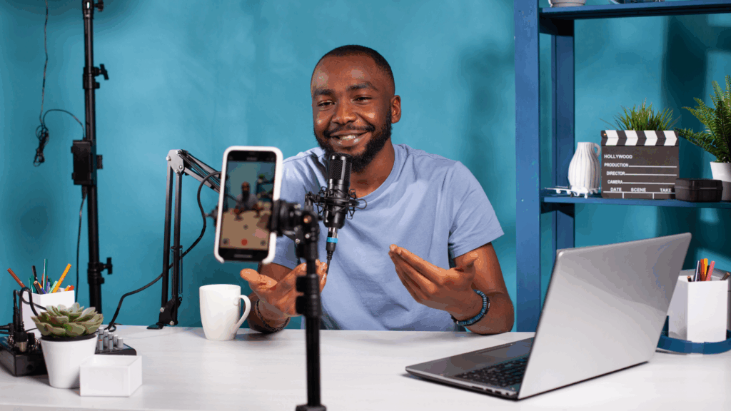 Content production Top 10 most successful businesses to start A man recording a podcast and filming it using a mobile phone.