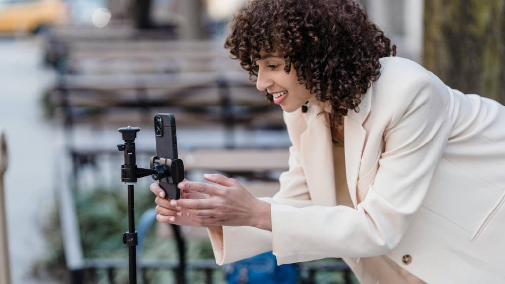 Create content and add your affiliate links A woman setting up a mobile phone on a tripod.