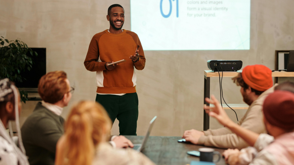 Easy pronunciation Shopify store names A smiling man presenting in front of a group of people in an office environment.