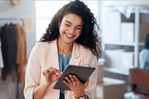 A woman smiles while using a tablet.