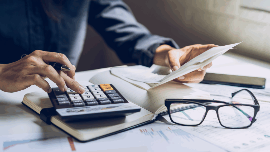 How to calculate profit margins High margin products Businesswoman calculating taxes with a calculator, focused on her work in a professional office setting.