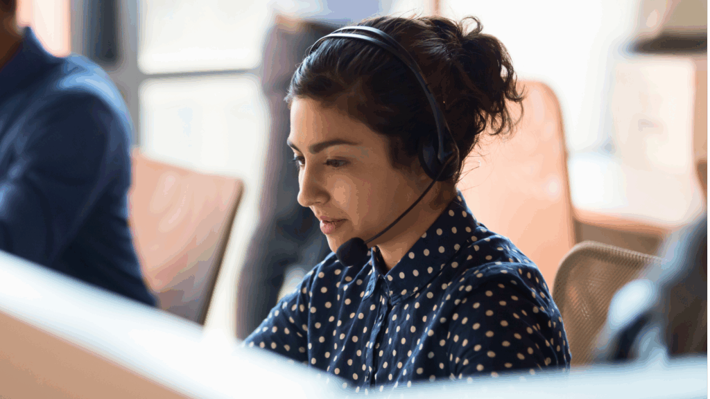 Improve customer service A woman wearing a headset, focused on her work in a modern office environment.