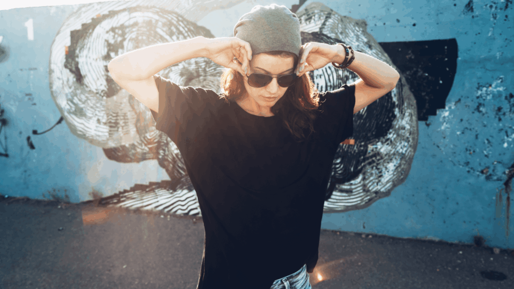 Measuring fabric weight A woman wearing sunglasses and a hat stands in front of a colorful graffiti wall, showcasing urban art.