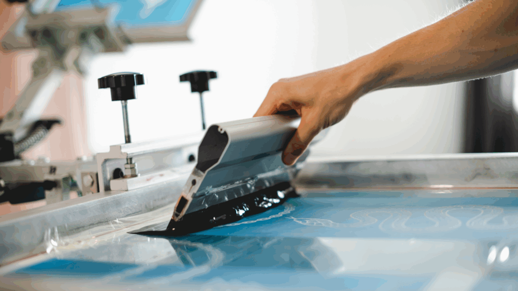 Modern screen printing A person engaged in printing on paper with a specialized machine.