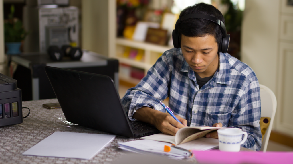 Online courses and tutoring Most profitable businesses A man with headphones focused on his laptop, engaged in work or a task.