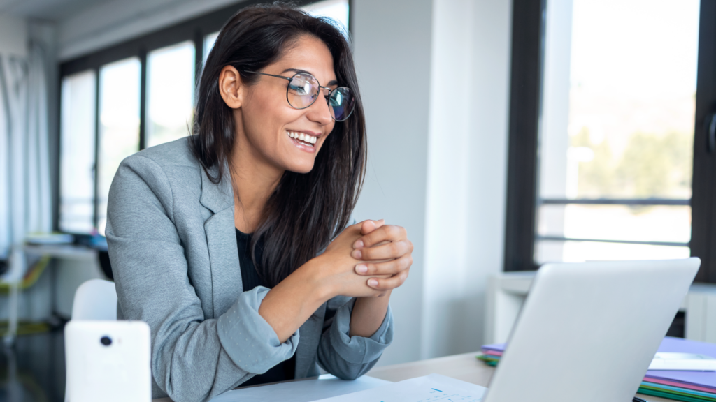 Online tutoring or coaching Side hustles that pay well A smiling woman in glasses is using a laptop, showcasing a moment of engagement and productivity.