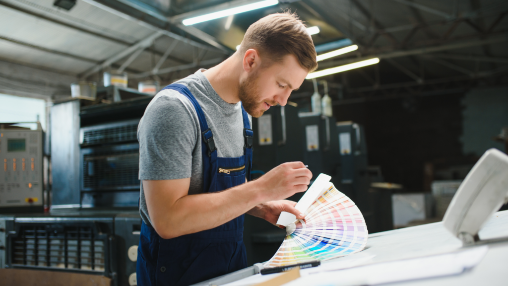 Print on Demand Remote side hustles A man in an office examines a color swatch, contemplating its application in his work environment.