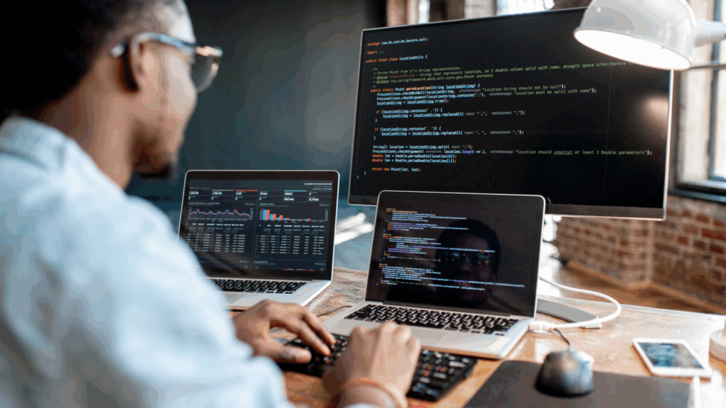 SaaS Top 10 most successful businesses to start A man coding using two laptops, with one laptop connected to the monitor.