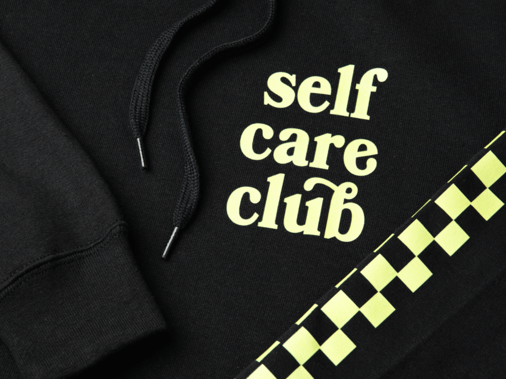 Sell print on demand products A black “Self-care club” hoodie close-up shot.