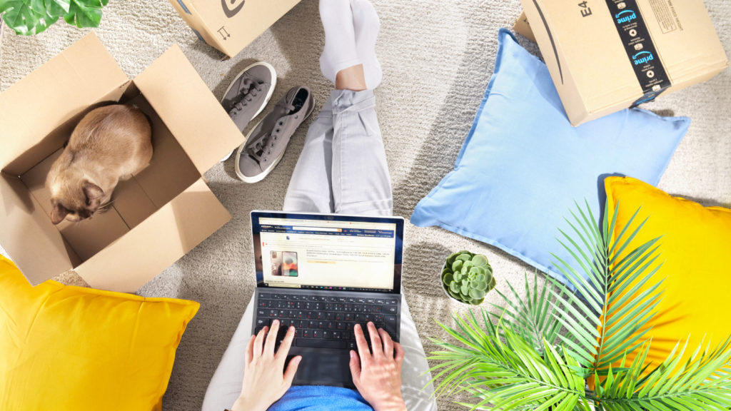Selling on Amazon 101 Tips for success A woman sitting on the floor with a laptop on her lap, surrounded by Amazon delivery boxes.