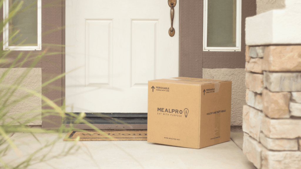 Shipping and t shirt weight A cardboard moving box is placed on the porch of a home, indicating a recent move or preparation for relocation.