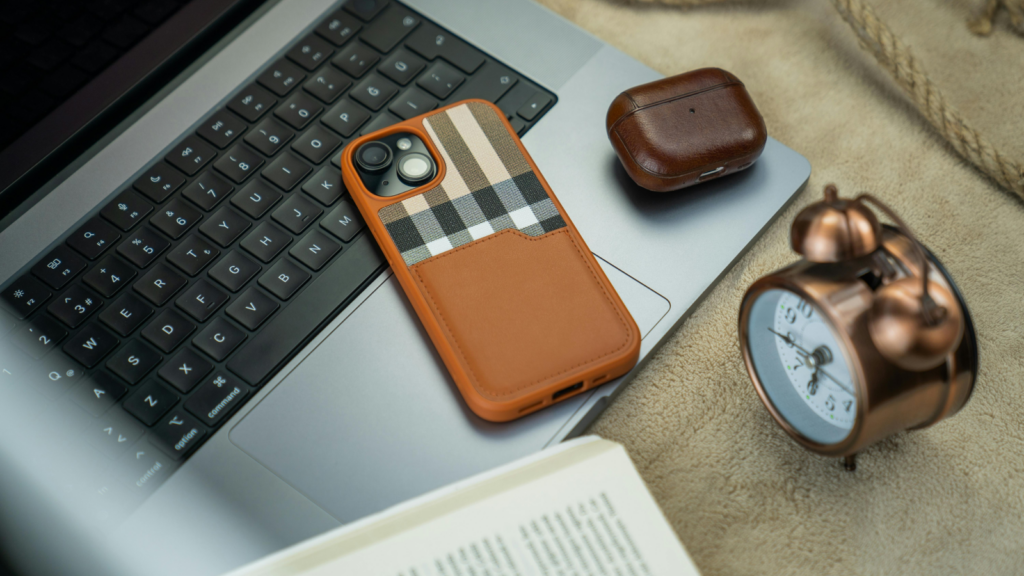 Smartphone accessories What to sell on Shopify A smartphone in a custom leather phone case lying on top of a laptop keyboard.