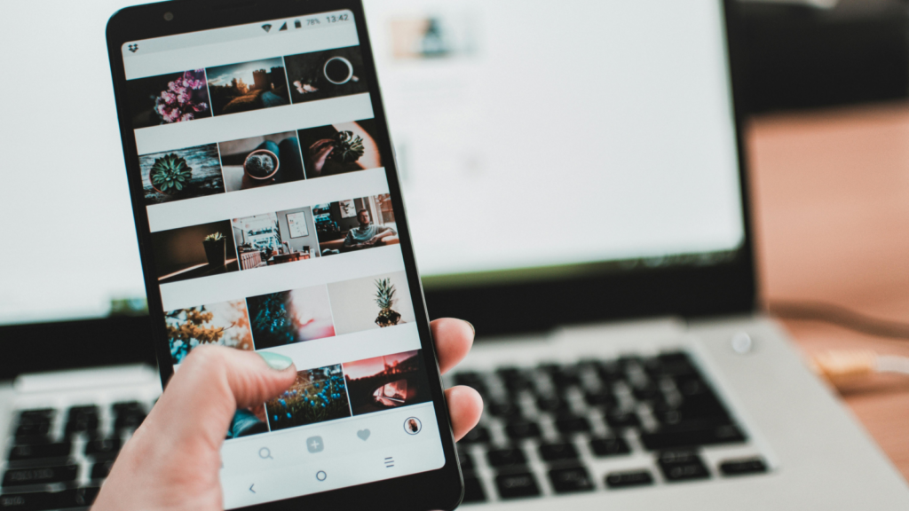 Steps to start social media affiliate marketing A woman holding a mobile phone in front of a laptop.