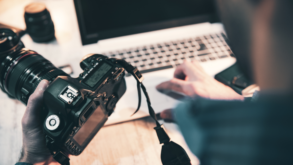 Stock photography and videography Remote side hustles A person holding a camera in one hand and a laptop in the other.