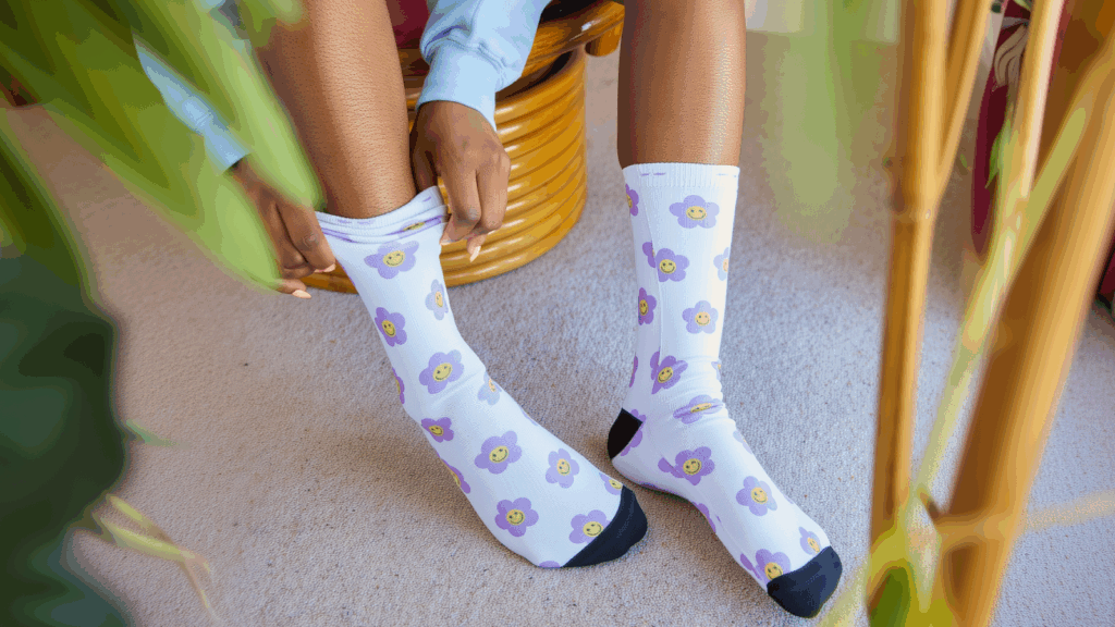Sublimation socks High margin products A woman displays her socks featuring a cheerful flower pattern, adding a playful touch to her outfit.