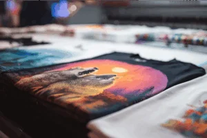 A freshly printed custom t-shirt with wolves in front of a large printer.