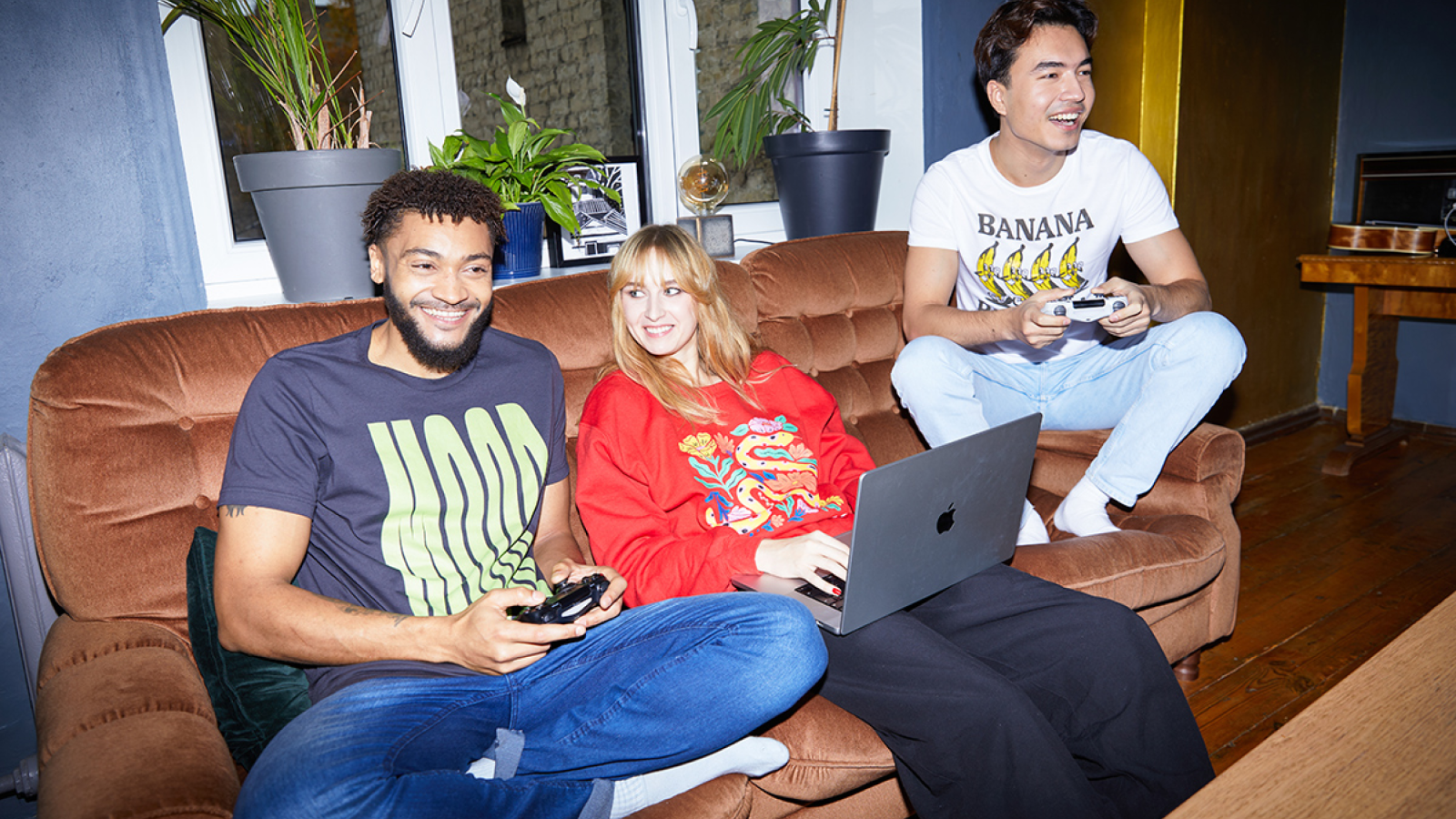 What different types of t shirt printing methods are available with Printify A group of people sitting on a couch in custom t-shirts and hoodies, playing video games.