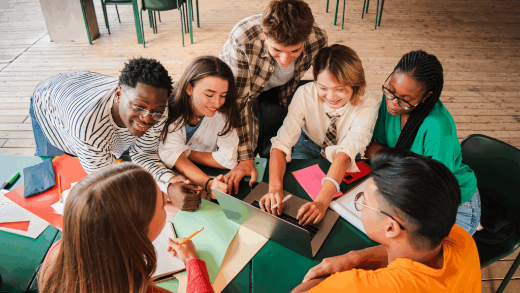 Why start a youth run business A group of young people around a table, debating on the best business ideas for teens.