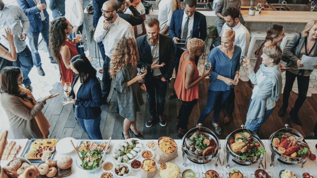 Attend networking events A group of people gathered around a buffet table filled with various dishes and food items.