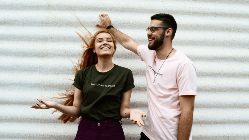 A man and a woman standing in different colored Next Level 3600 t-shirts.
