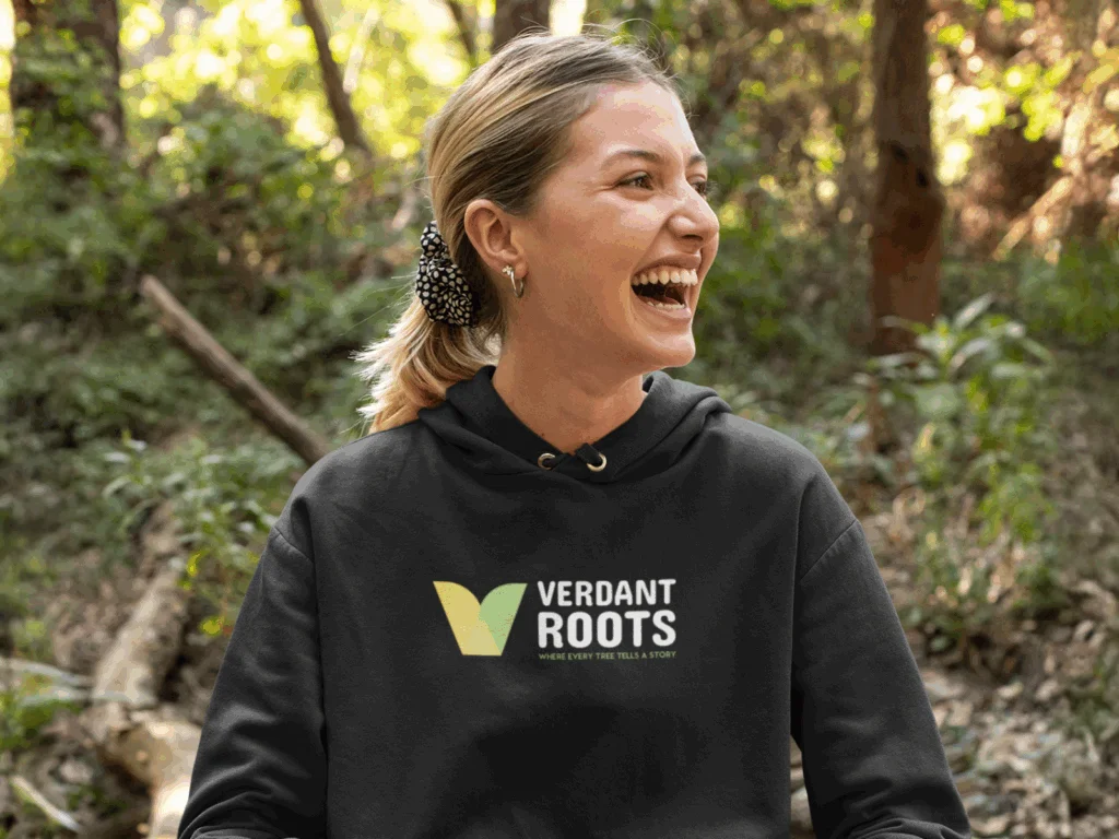 A smiling woman is wearing a black hoodie with a chest print of a company logo.