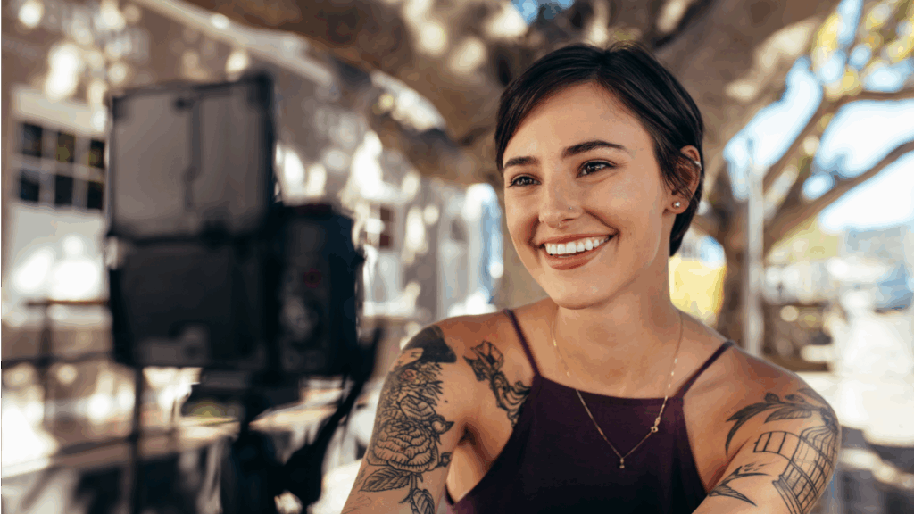 Create a YouTube channel A smiling woman with tattoos poses for the camera, showcasing her joyful expression.