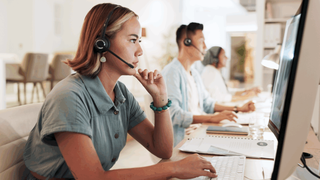 A woman wearing a headset, focused on her work in a modern office environment.