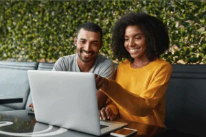 A smiling man and woman using a laptop to search for Etsy shop names.