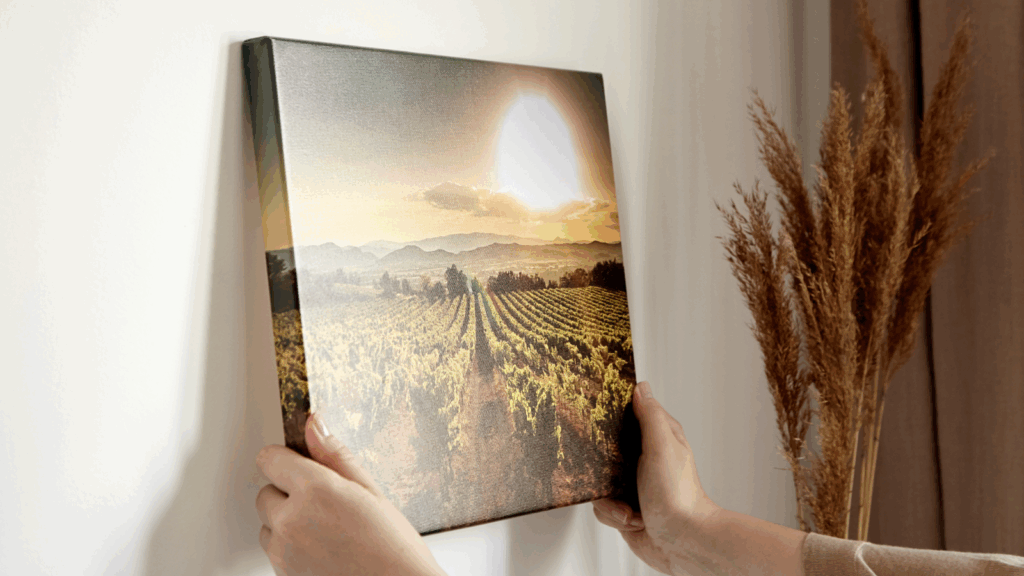 Finish and mount your canvas A person is putting a canvas print of a field on a wall.
