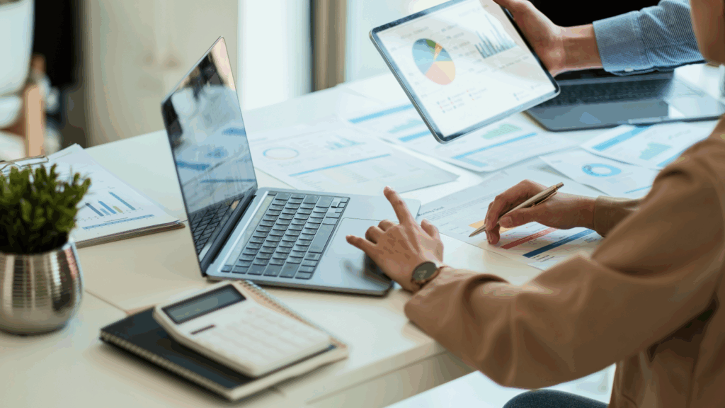 First steps to starting a business Business professionals collaborating at a table with laptops and documents spread out in a modern office setting.