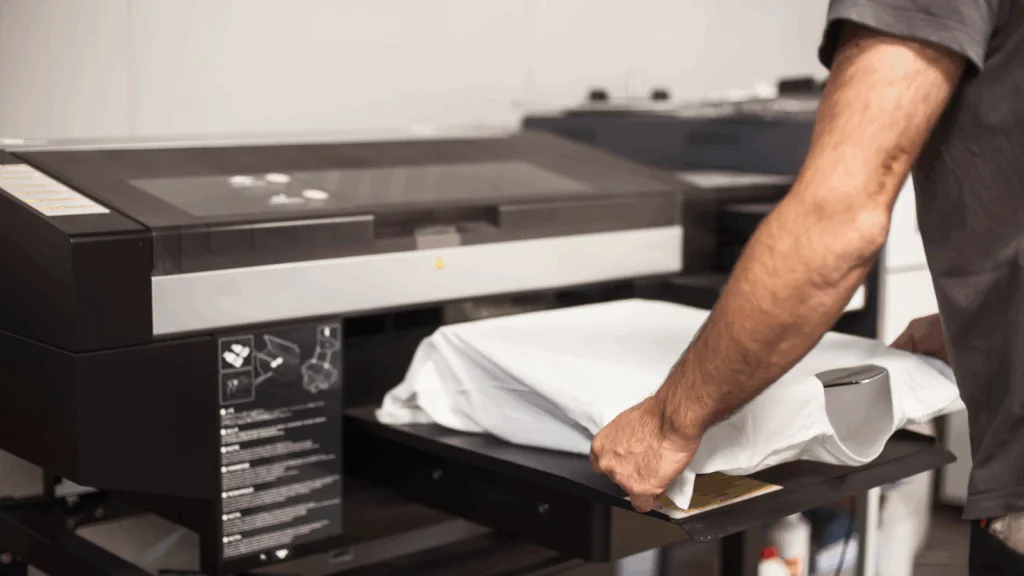 A man is preparing a white t-shirt for printing.