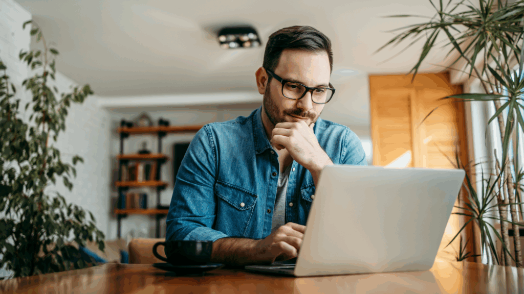 Market your dropshipping business A man in glasses is sitting at a desk and using a laptop.