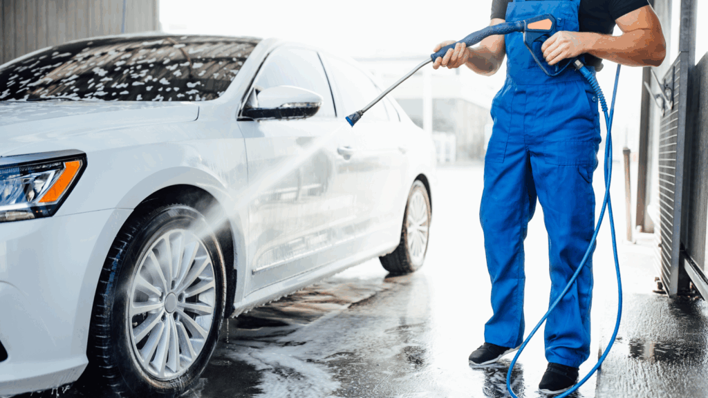 Offer mobile car washes – Clean vehicles on site anywhere A man in overalls washes a white car.