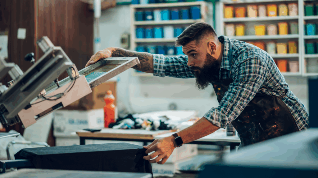 Print on Demand – Sell custom products with your designs A man is making a print on a fabric.