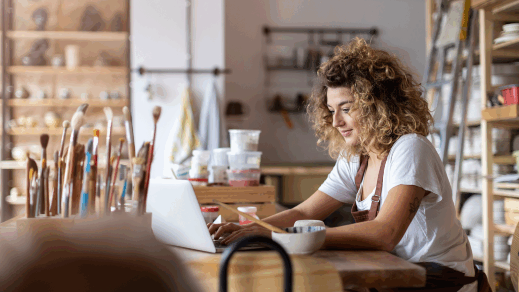Promote your art store An artist is sitting in a studio, using a laptop.