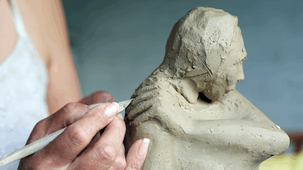 Sculptures and mixed media pieces A woman holds a clay sculpture depicting a man.